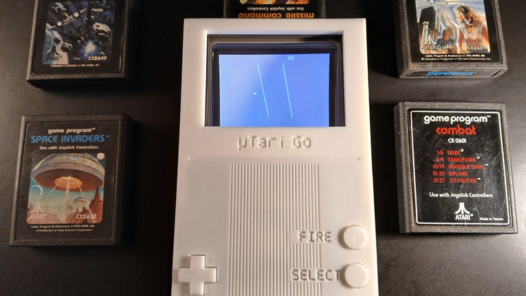 La portable µTari Go, blanche et très longiligne, avec une petite croix directionnelle et trois boutons alignés verticalement, très loin d'un petit écran tout en haut de la machine